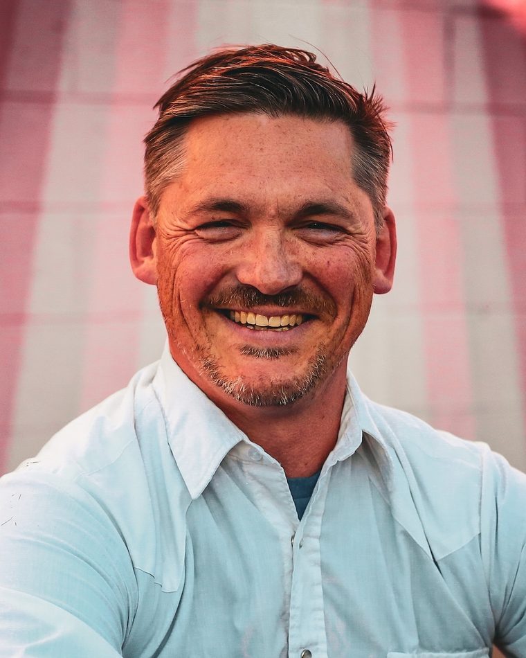 Brian Lynn, founder and creative strategist of Semaphore Strategy, smiling in front of a striped mural